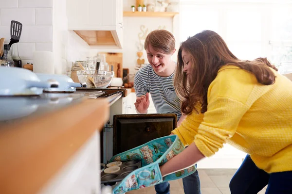 Jovens Downs Síndrome Casal Colocando Cupcakes Caseiros Forno Cozinha Casa — Fotografia de Stock