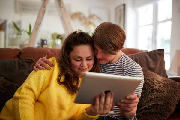 爱年轻的唐氏综合症夫妇坐在坐在一个使用数字平板电脑在家里 — 图库照片