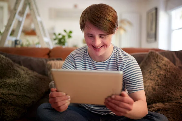 Young Downs Syndrom Man Sitter Soffan Med Digital Tablet Hemma — Stockfoto