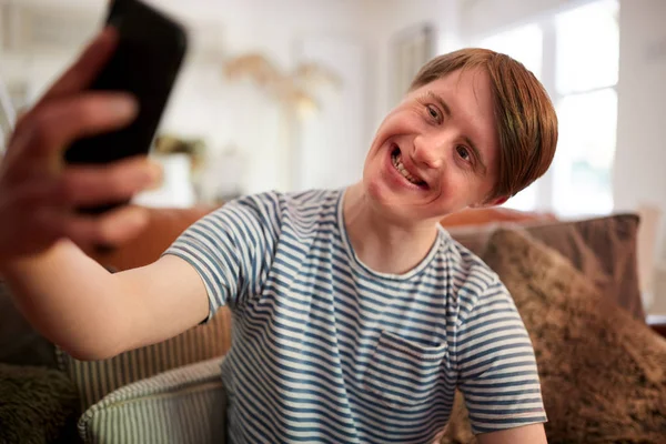 Young Downs Syndrome Man Sitting Sofa Using Mobile Phone Take — Stock Photo, Image