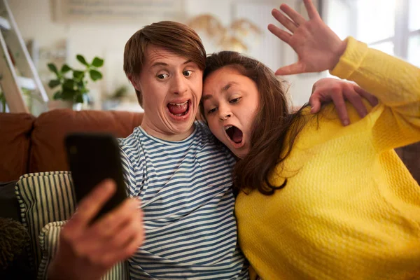 Young Downs Oireyhtymä Pari Istuu Sohvalla Kännykän Avulla Ottaa Selfie — kuvapankkivalokuva