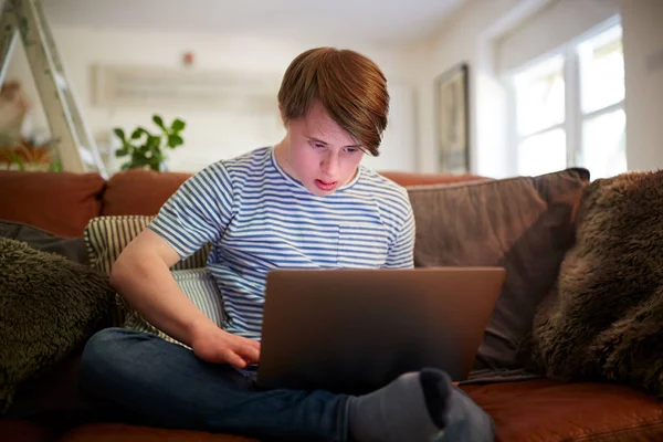 Jovem Downs Síndrome Homem Sentado Sofá Usando Laptop Casa — Fotografia de Stock