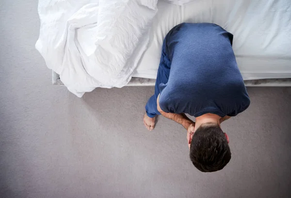 自宅のベッドに座ってうつ病に苦しむパジャマを着た男の頭上の眺め — ストック写真
