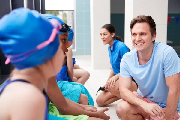 Manlig Tränare Barn Simning Klass Briefing Som Sitter Kanten Inomhuspoolen — Stockfoto