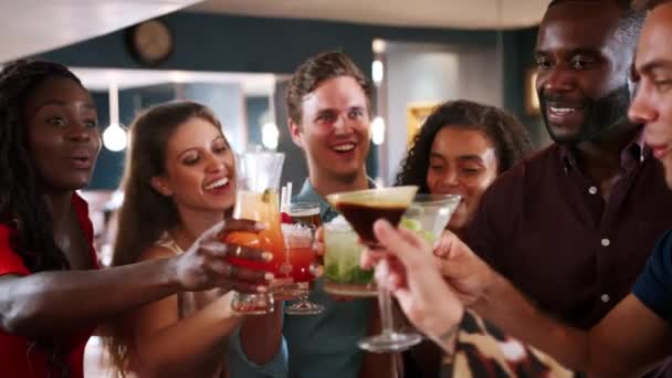 一緒に乾杯するカクテルバーで飲み物のために会う若い友人のグループ スローモーションでビデオ撮影 — ストック動画