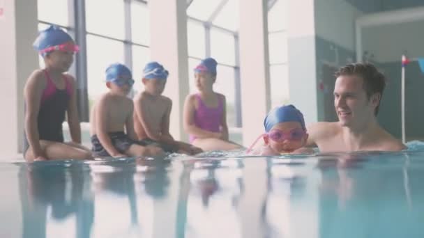 Male Swimming Teacher Giving Girl Holding Float Lesson Pool Shot — Wideo stockowe