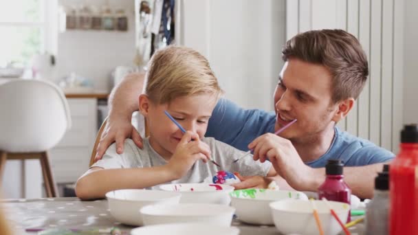 Father Sitting Kitchen Table Helping Son Paint Eggs Easter Shot Video Clip