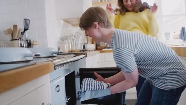 Young Downs Syndrome Couple Taking Homemade Cupcakes Out Oven Kitchen — Stock Video