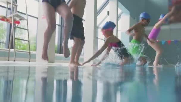 Tiro Subaquático Crianças Pulando Piscina Interior Borda Filmado Câmera Lenta — Vídeo de Stock