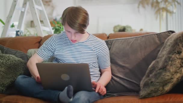Joven Hombre Síndrome Downs Sentado Sofá Casa Con Ordenador Portátil — Vídeos de Stock