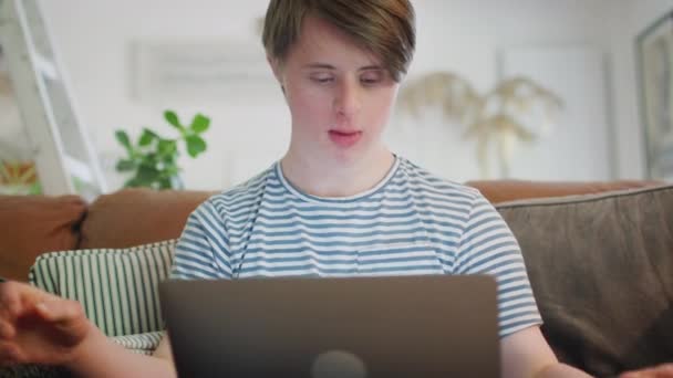 Νεαρός Άνδρας Σύνδρομο Downs Κάθεται Στον Καναπέ Στο Σπίτι Χρησιμοποιώντας — Αρχείο Βίντεο
