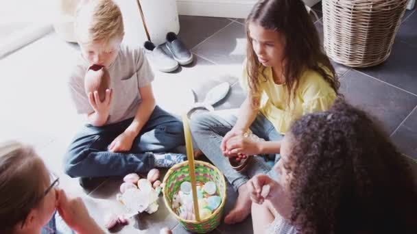 床の上に座っている子供たちのグループのオーバーヘッドビュー屋内オープンし チョコレートイースターエッグを食べる スローモーションで撮影 — ストック動画