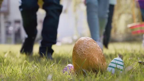 イースターエッグハントの子供たちのグループの閉鎖は チョコレートの卵に向かって庭を走っています スローモーションで撮影 — ストック動画