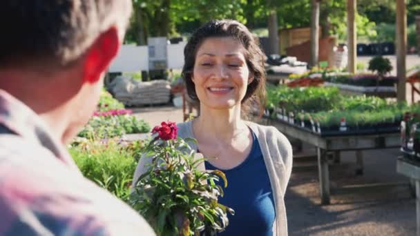 笑顔成熟した女性は屋外ガーデンセンターで男性販売アシスタントから植物を購入 スローモーションで撮影 — ストック動画