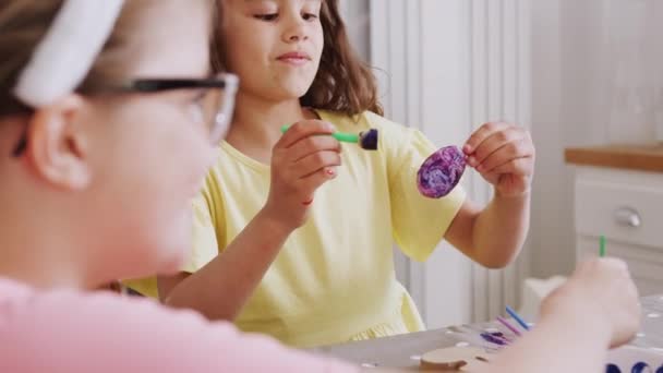 Twee Meisjes Zitten Rond Keukentafel Dragen Konijnenoren Versieren Eieren Voor — Stockvideo