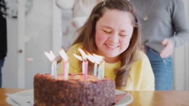 若いですダウン症候群カップルお祝いの誕生日吹いてキャンドルアウトケーキに家 ショットでスローモーション — ストック動画