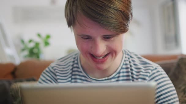 Young Downs Syndrome Hombre Sentado Sofá Viendo Transmisión Películas Tableta — Vídeo de stock