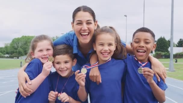 女子監督がスポーツの日に獲得したメダルを披露する子供たちの肖像 スローモーションで撮影 — ストック動画
