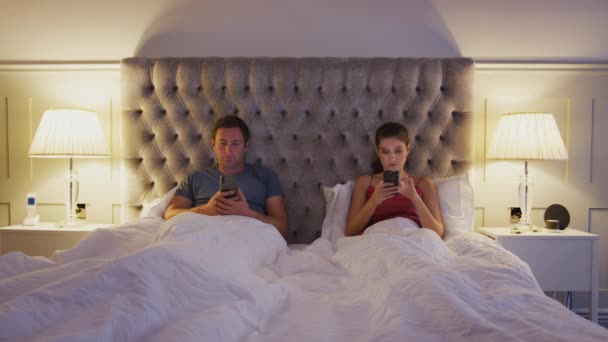 Çift Yatakta Yan Yana Uzanmış Cep Telefonlarını Kontrol Ederken Birbirleriyle — Stok video