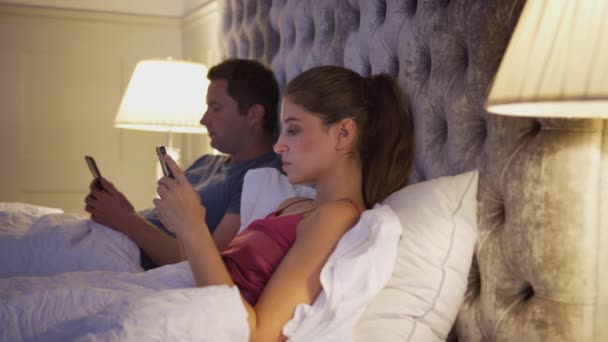 Couple Lying Next Each Other Bed Checking Mobile Phones Whilst — Stock Video