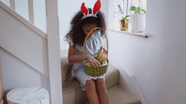 Flicka Klädd Kanin Öron Sitter Trappor Hemma Äta Choklad Ägg — Stockvideo