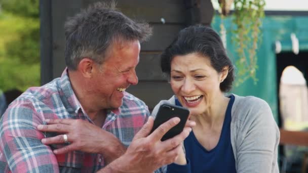 Volwassen Paar Zitten Aan Tafel Kijken Naar Foto Mobiele Telefoon — Stockvideo
