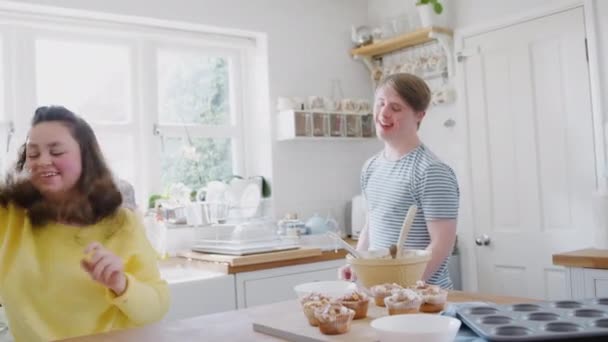 年轻的唐斯综合症夫妇在厨房里跳舞 一边用冰块和棉花糖装饰杯子蛋糕 动作缓慢 — 图库视频影像