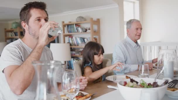 一緒に食事を楽しむ家庭でテーブルの周りに座っている世代の家族 スローモーションで撮影 — ストック動画