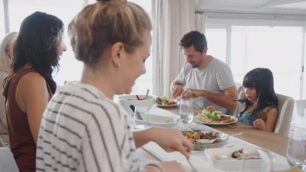 一緒に食事を楽しむ家庭でテーブルの周りに座っている世代の家族 スローモーションで撮影 — ストック動画