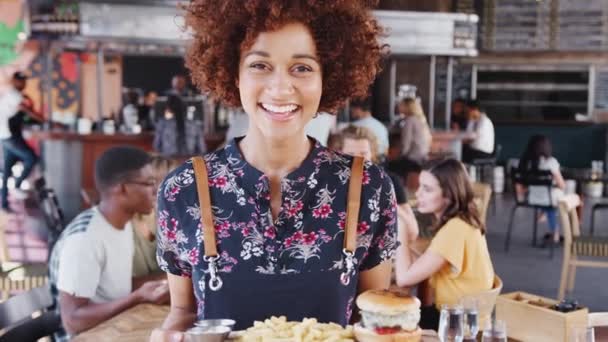 在繁忙的酒吧餐厅拿着一盘子汉堡包和薯条的女服务员的画像 慢镜头拍摄 — 图库视频影像