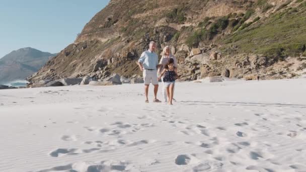孫と祖父母で夏休み先に実行している女の子と砂浜に沿って歩く スローモーションで撮影 — ストック動画