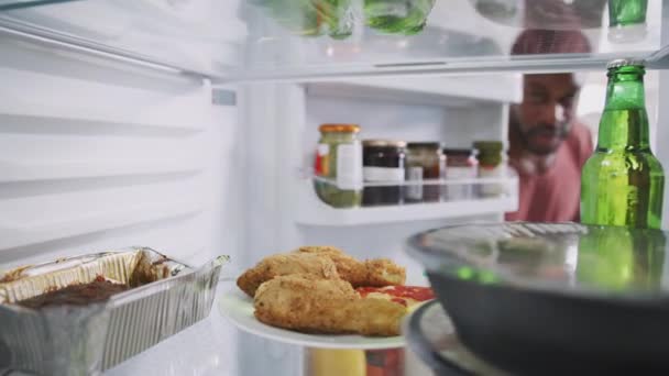 从冰箱里往外看 男人打开门 拿出一盘不健康的剩菜 外卖炸鸡和披萨 动作缓慢 — 图库视频影像
