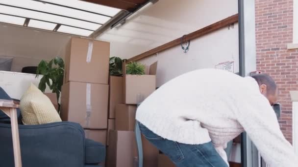 移動中の日に新しい家にボックスを荷降ろしトラックの後ろに立っている男 スローモーションで撮影 — ストック動画