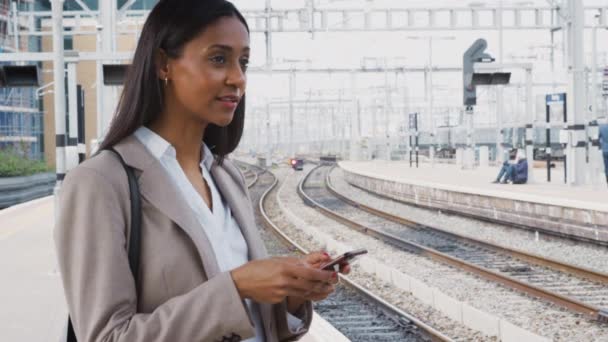 通勤電車のホームに立っているビジネスマンの女性は携帯電話を使用して作業する スローモーションで撮影 — ストック動画