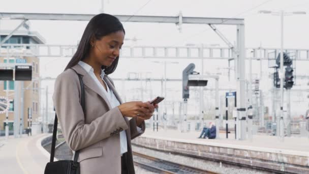 通勤電車のホームに立っているビジネスマンの女性は携帯電話を使用して作業する スローモーションで撮影 — ストック動画