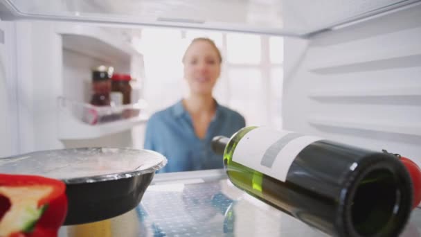 若い女性がドアを開き ワインと利便性の準備ができて食事のボトルを取り出し 冷蔵庫内からの眺め スローモーションで撮影 — ストック動画