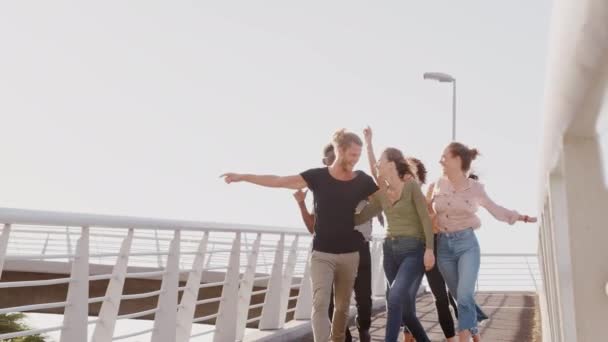 Grupo Amigos Caminhando Através Ponte Cidade Contra Sol Flamejante Tiro — Vídeo de Stock