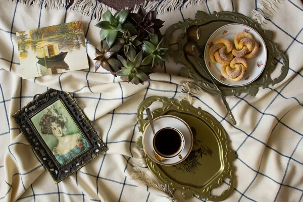 Antique dishes on a table with a checkered tablecloth, nearby are old paintings — Stock Photo, Image