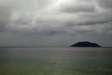     Yağmurda deniz. Eylül ayında bulutlu bir gün. Kıyıdan adanın görünümü. Güzel bulutlar.                           
