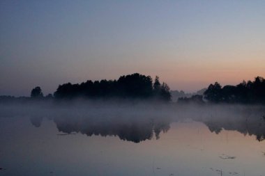       Eylülde gölün üzerinde sisli bir sabah. Hint yazı ve gündoğumu. Sıcacık sonbahar manzarası.                          