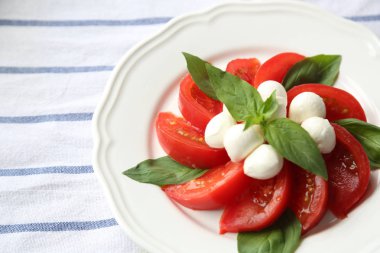 Domates Mozzarella peyniri ve fesleğen yaprak beyaz bir plaka üzerinde