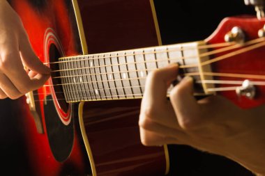 Akustik gitar kırmızı, koyu arka plan, oturur klasik İspanyol, müzikal okul klavye ve dizeleri, üzerinde çocuklar ve yetişkinler yakın çekim için oyun enstrümanın mikrofondaki oynarken müzisyen