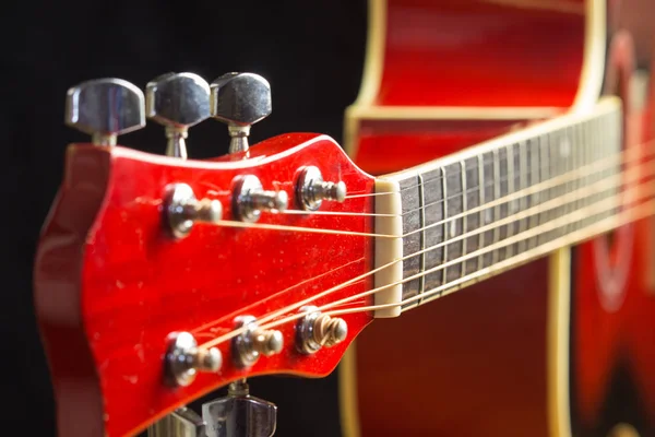 Acoustic red guitar resting in the background with a copy of the hand space, playing acoustic guitar, close-up on the desktop