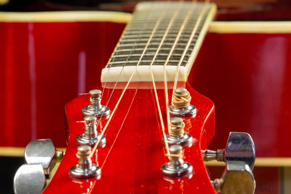 Guitarra vermelha acústica encontra-se sobre a mesa em segundo plano com uma cópia do espaço de mão, tocando guitarra acústica, close-up de prancha e cordas, deck de instrumentos, papel de parede — Fotografia de Stock