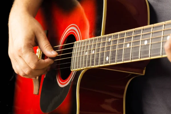 Akustik gitar kırmızı, koyu arka plan, oturur klasik İspanyol, müzikal okul klavye ve dizeleri, üzerinde çocuklar ve yetişkinler yakın çekim için oyun enstrümanın mikrofondaki oynarken müzisyen