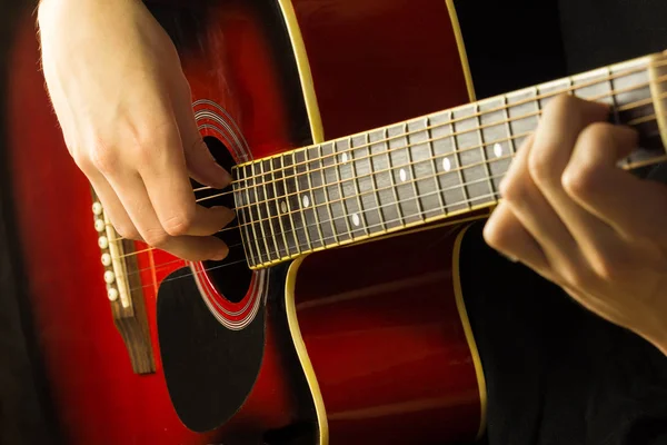 Akustik gitar kırmızı, koyu arka plan, oturur klasik İspanyol, müzikal okul klavye ve dizeleri, üzerinde çocuklar ve yetişkinler yakın çekim için oyun enstrümanın mikrofondaki oynarken müzisyen