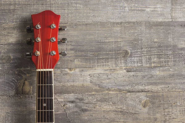 Guitar acoustic red, neck lying on a vintage background of wood on the background of old grunge boards. Place for text. View sverkhplastichnost Spanish, rectangular format music school game for Royalty Free Stock Photos