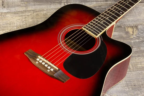 Guitar acoustic red, neck lying on a vintage background of wood on the background of old grunge boards. View sverkhplastichnost Spanish, of fingerboard and strings, the soundboard of the instrument