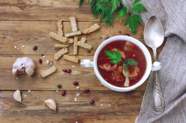 Beyaz kase, vintage kaşık, baharatlı otlar, sarımsak, Peksimet ahşap masa, rustik tarzı üzerinde Füme pastırma ile kırmızı fasulye çorbası