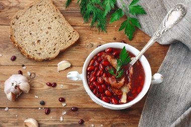 kırmızı fasulye çorbası beyaz kase, vintage kaşık, baharatlı otlar, Füme pastırma ile sarımsak, tahıl ekmek ahşap masa, rustik tarzı, portre